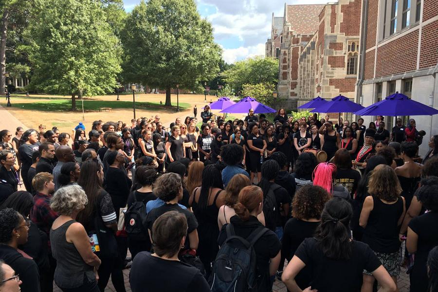 A large group of people wearing black gather outside that Alston Campus Center.
